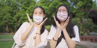 亚洲少女姐妹戴着口罩微笑应对新冠肺炎疫情