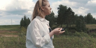 一个女孩站在田野里，操控着一架无人机