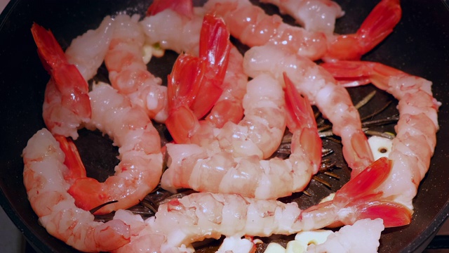 生虾在平底锅里烤在黑色背景。新鲜海鲜食材-虾尾即可烹煮，无需腌料。虾在锅里