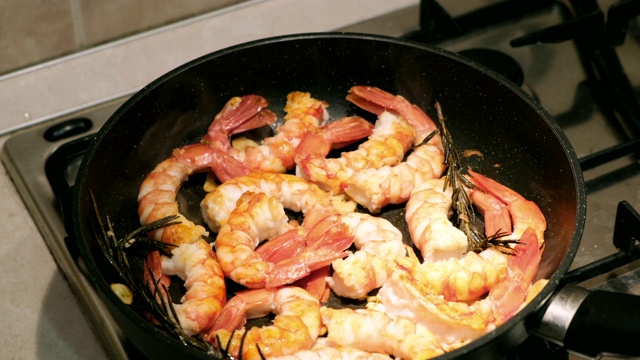 生虾在平底锅里烤在黑色背景。新鲜海鲜食材-虾尾即可烹煮，无需腌料。虾在锅里