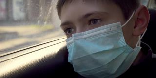 一个戴着医用口罩的小男孩在街上向车窗外望去。闭关锁国则在摧毁检疫