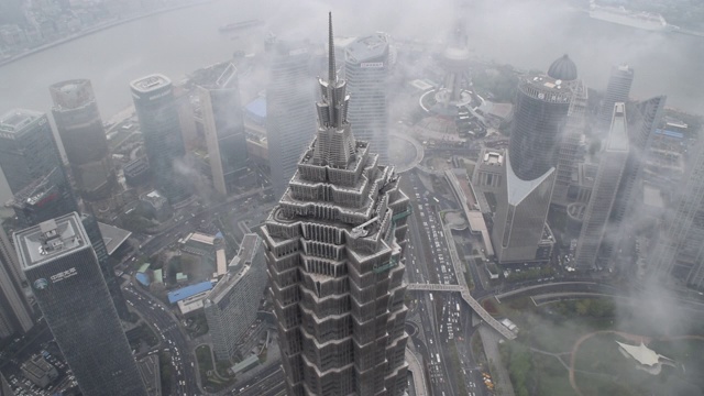 令人惊叹的时间流逝:金茂大厦被雾包围，云彩掠过，街道上的汽车交通高峰时段摩天大楼白天，阴天