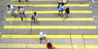 在香港孟角区，一群无法辨认的行人和汽车在黄色斑马线上行走