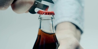 一名男子用开瓶器打开装有冷却饮料的玻璃瓶中的金属软木塞