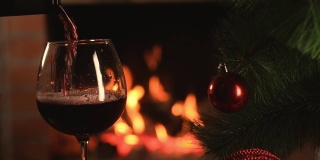 在燃烧的壁炉的背景下，葡萄酒倒进玻璃杯