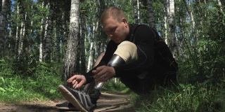 一个装着假肢的运动员正在跑步后休息，并系上鞋带