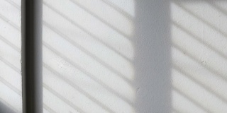 时间流逝:阳光的背景透过窗户照在白色的混凝土墙上。