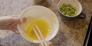 一个女人用筷子打鸡蛋准备做饭