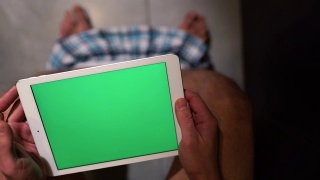 男人坐在厕所的壶上。手持平板电脑，放大和滑动。绿色的屏幕。独自在厕所里。裤子躺在脚上。腹泻视频素材模板下载