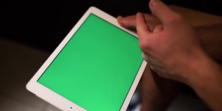 拍摄过程视频，人拿着平板电脑，向右滑动。绿色的屏幕。坐在厕所或休息室里的家伙。