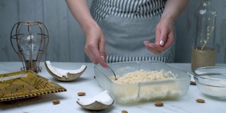 女人的手正在准备椰子巧克力碗。将干燥的椰子、枫糖浆和椰子黄油搅拌在一起，揉搓成碗状。手工巧克力的概念。