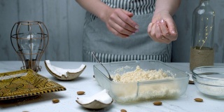 女人的手正在准备椰子巧克力碗。将干燥的椰子、枫糖浆和椰子黄油搅拌在一起，揉搓成碗状。手工巧克力的概念。
