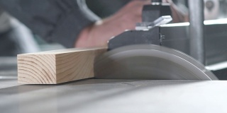 一名专业工人用金属圆锯片切下一块木板。