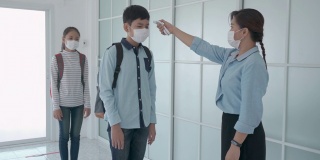 亚洲女教师在学生返校时使用体温计检查学生体温，以防止COVID-19的传播，新常态和教育理念。