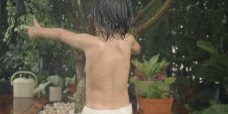 亚洲婴儿在自家前院笑着玩水。