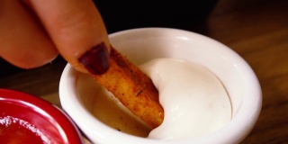慢镜头:脆脆的薯条和蛋黄酱被人用手吃。