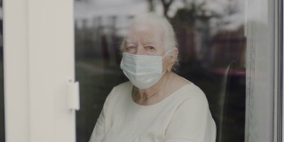 戴医用面具的老妇人肖像。看窗外的女人。