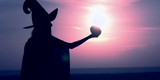 一个穿着女巫服装的女人举起一个有魔力的苹果