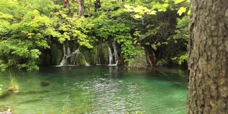 平移运动显示一个小美丽宁静的瀑布在克罗地亚普利特维茨湖自然公园。新冠肺炎疫情爆发后，公园在温暖的夏日开放，绿意盎然