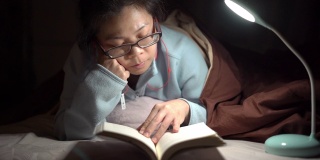 一个亚洲女人晚上在床上看书