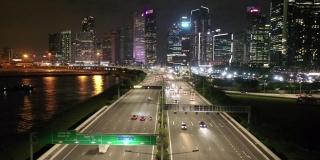 在新加坡，无人机在夜间拍摄高速公路上的交通和城市天际线