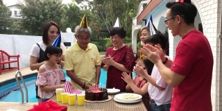 一个亚裔华人家庭在前院游泳池旁为活跃的老爷爷庆祝生日