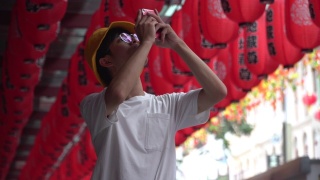 一名男子在街上拍摄红灯笼装饰视频素材模板下载