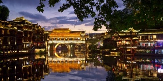 中国凤凰。夜晚的景观与明亮的灯光照明。桥映沱江。人们玩得很开心。平移,UHD