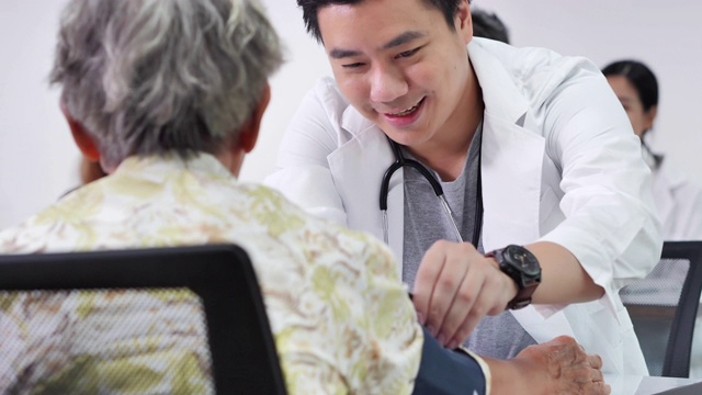 快乐组志愿者亚洲年轻男护士医生检查身体压力亚洲老年妇女，以预防流行病和咨询亚洲老年妇女病人。医疗、照顾、退休、志愿者、教育、医疗和药品