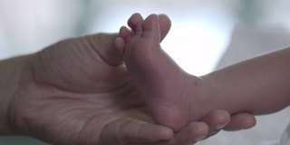 当她的宝宝在温柔和爱中睡觉时，妈妈靠近新生儿的脚。幸福的家庭的概念。