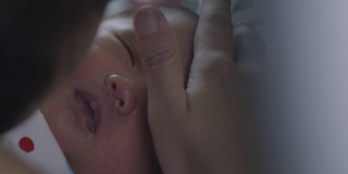 靠近可爱的亚洲新生女婴正在睡觉和母亲触摸她的脸与温柔和爱。幸福的家庭的概念。