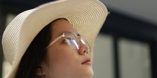 特写的肖像年轻的亚洲妇女戴着软呢帽和眼镜环顾在老城。旅游探索理念，夏日度假。