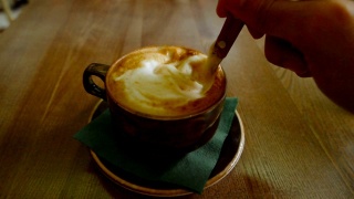 一个男人在杯子里搅拌卡布奇诺咖啡视频素材模板下载