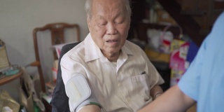 家庭护士试图给成年老人做血压测试