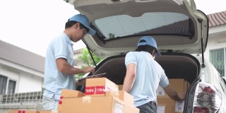 两个人往汽车后备箱里装纸箱，用写字板检查订单