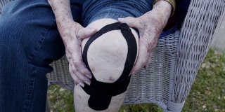 特写镜头老年白人妇女的膝关节关节炎疼痛在正午户外在夏天