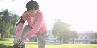 一名华裔老年妇女早上在公园锻炼伸展她的腿