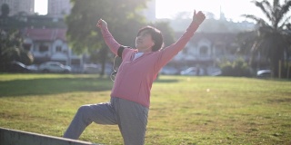 一名华裔老年妇女早上在公园锻炼伸展她的腿