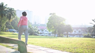 一位华裔老年妇女在公园晨练，在人行道上跑步视频素材模板下载