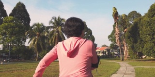 一位华裔老年妇女在公园晨练，在人行道上跑步