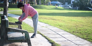 一位亚裔中国老年妇女早上在公园里锻炼，系着她的鞋子