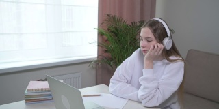 一个年轻女孩厌倦了在线学习。戴着耳机。