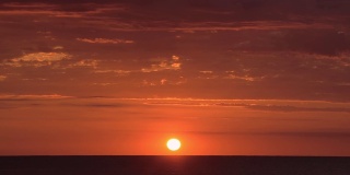 明亮的红色和橙色的日落风景在海洋上，很少有云