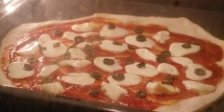 准备自制的玛格丽塔披萨，用西红柿，橄榄，奶酪放在热烤箱里。间隔拍摄