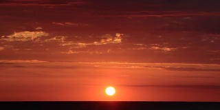明亮的红色和橙色日落的时间流逝，在海洋上，很少有云