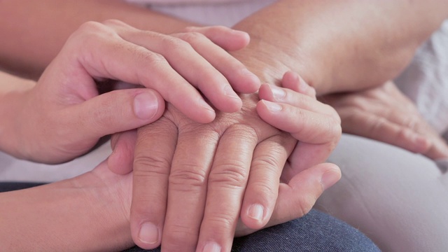 亚洲女性护理员牵着老祖母病人的手，帮助表达同情，鼓励告知诊断。老年人保健，老年人护理