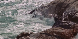 大浪拍打着海岸，溅起白色的泡沫。海浪冲击岩石
