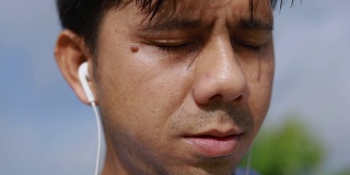 近距离观察亚洲男性在运动后会擦去额头上的汗水。