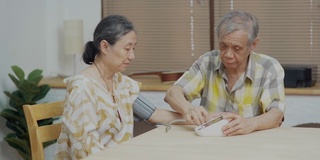 老年男子在家为老年妇女检查血压