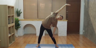 正面的观点，成熟的妇女训练瑜伽姿势在练习垫在家里